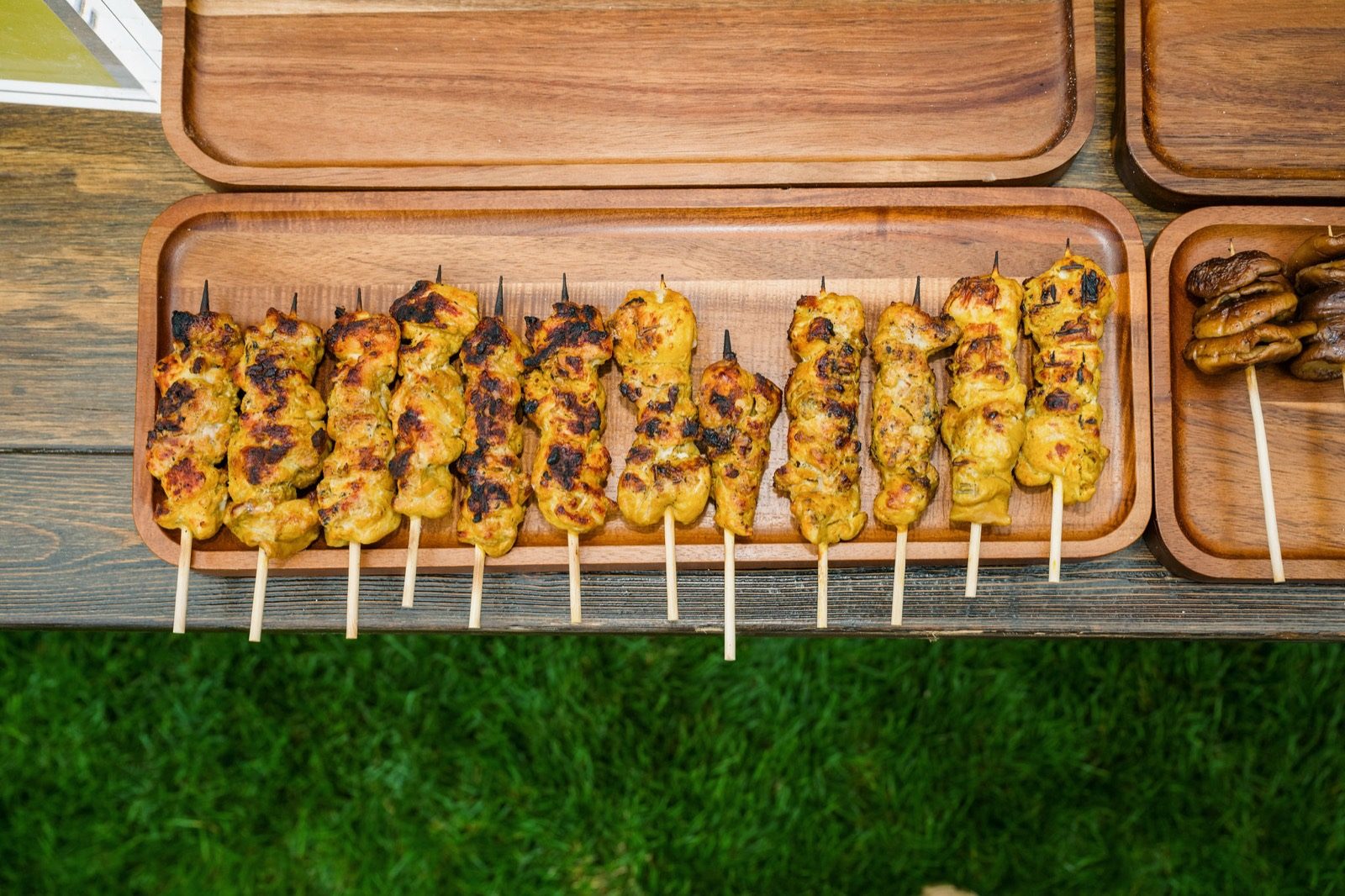 Curry chicken skewers laid out on wooden trays