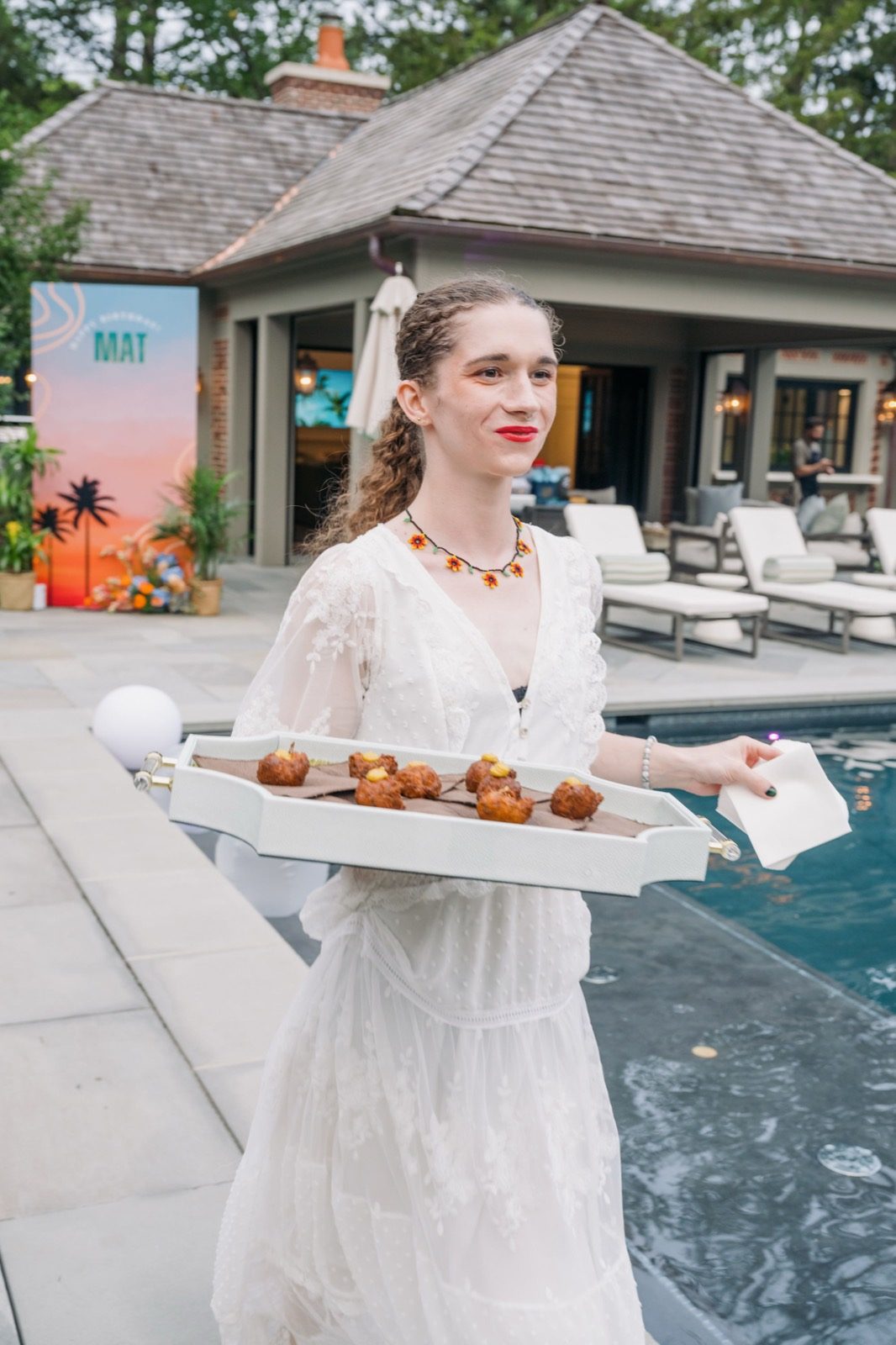 A server carrying a tray of passed bites along the pool