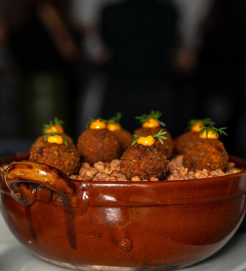 Short rib arancini with chili crema in a glazed ceramic pot