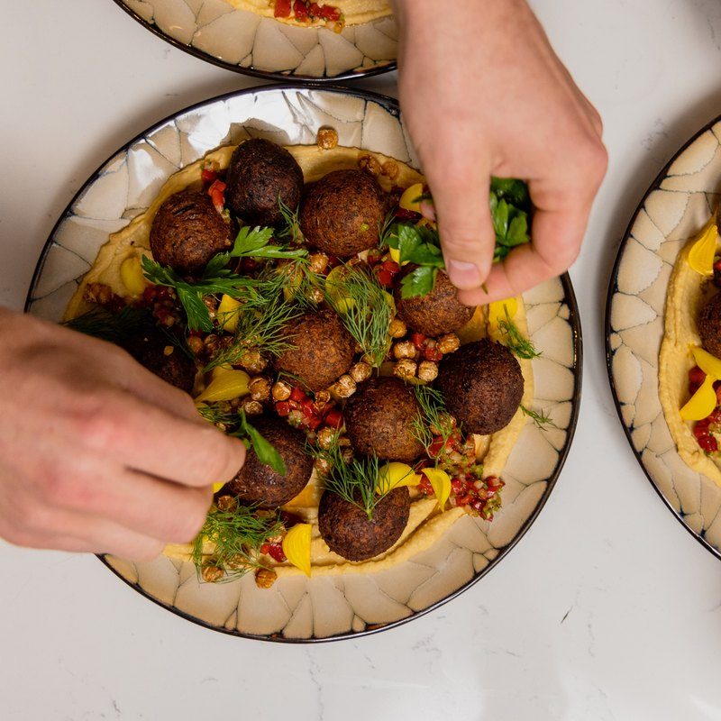Falafel and hummus platters being finished by hand
