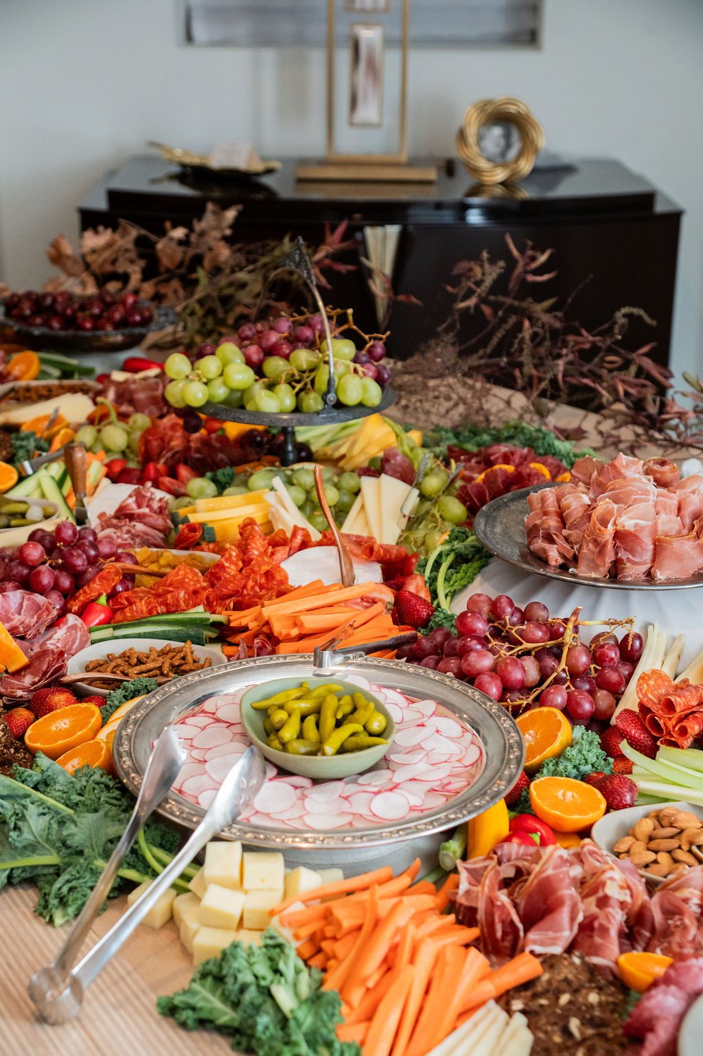 A sprawling grazing table of charcuterie, cheese, and seasonal fruit