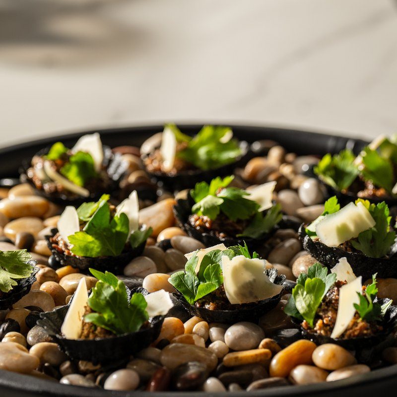 Mushroom duxelles with pecorino in buckwheat tarts, plated on black river stones