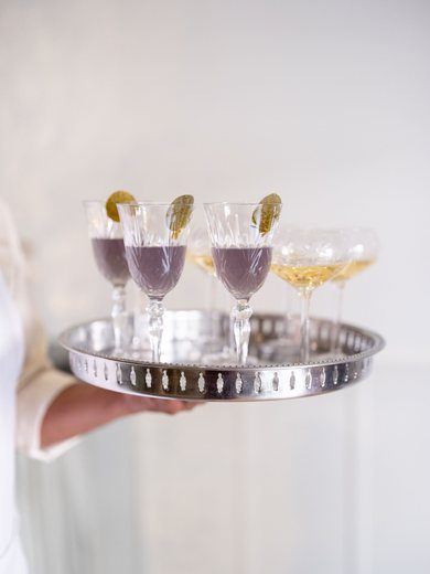 Champagne and cocktails passed on a silver tray against a white backdrop